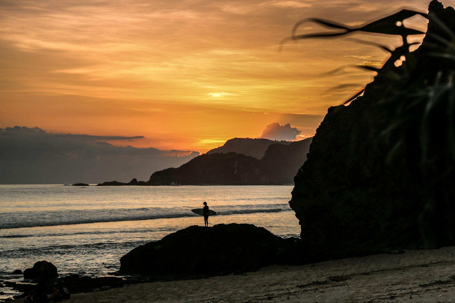 Silhouette at sunset on a rock by the water, Lombok